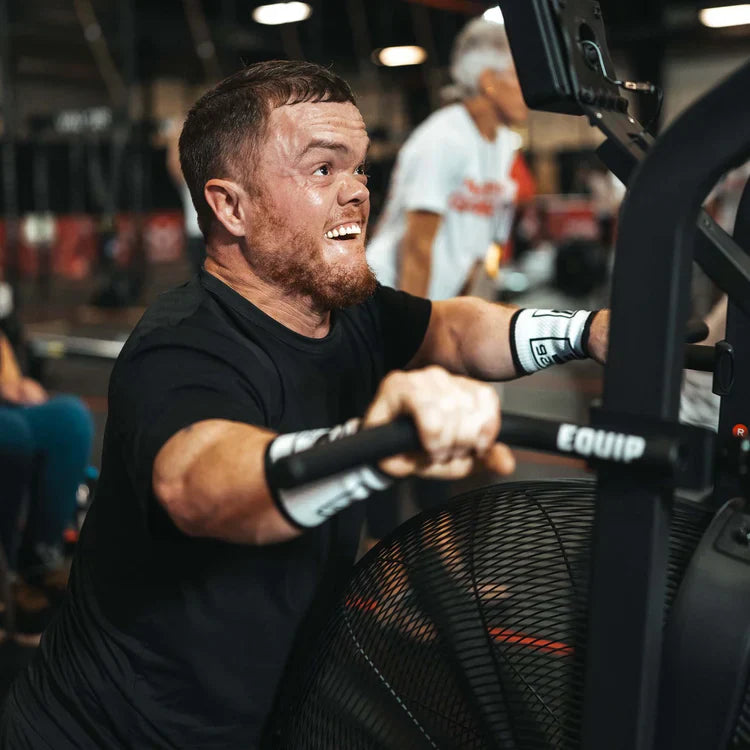 A CrossFit competitor with short stature using an assault bike.