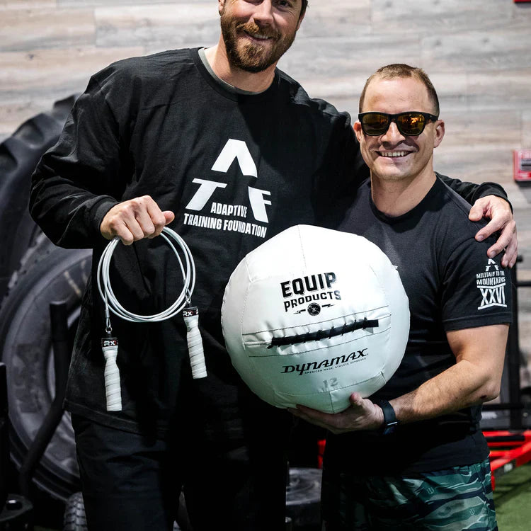 A CrossFitter with a visual impairment holding Equip Products jump rope and medicine ball with their training partner.