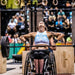 Equip Products Black Small LapMat™ in use during a CrossFit competition with a competitor in a wheelchair lifting a barbell with weights on the end.