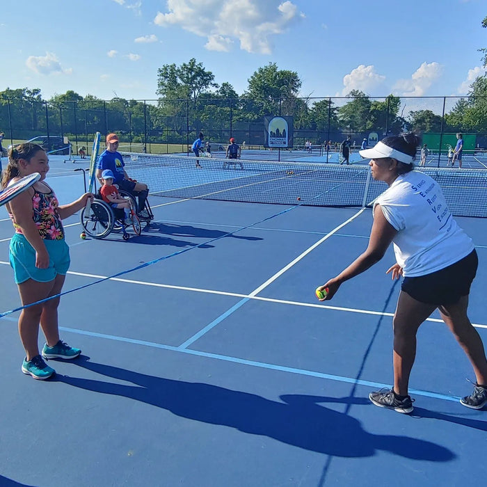 Cincinnati Tennis Foundation beginner adaptive spring tennis participant being served a ball by the coach.