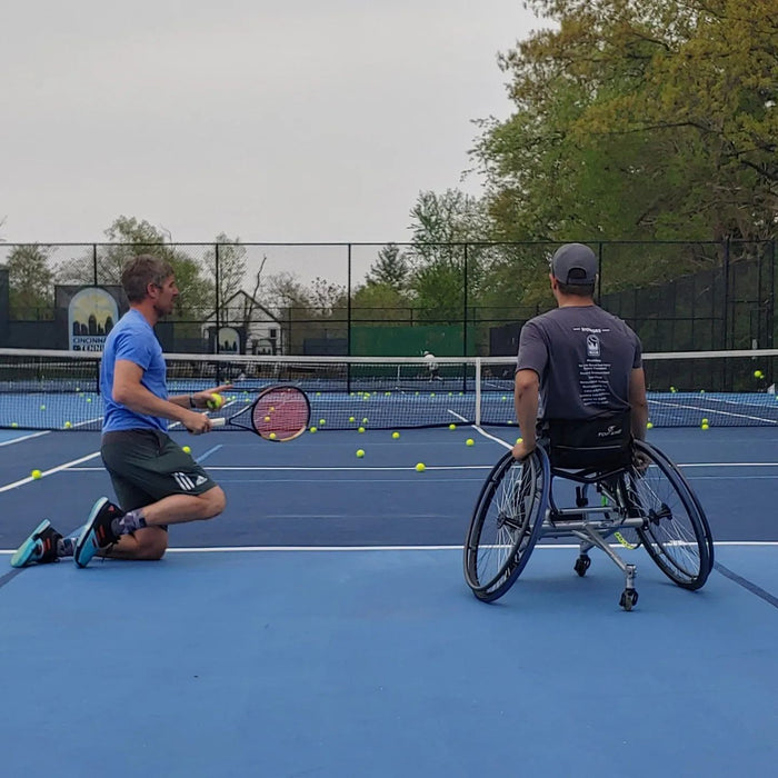 A coach getting ready to serve with a Cincinnati Tennis Foundation advanced wheelchair tennis participant.