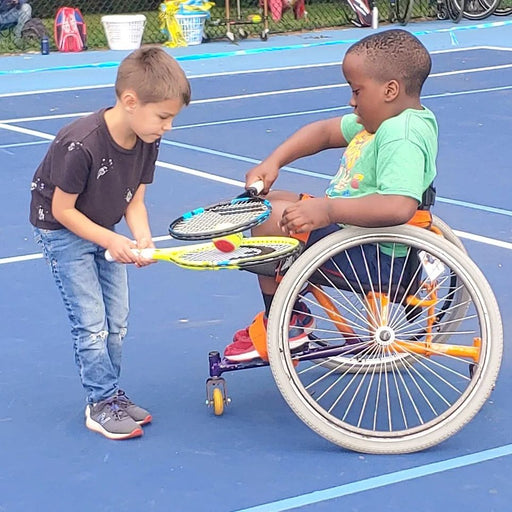 Cincinnati Tennis Foundation intro to wheelchair tennis participants holding a tennis ball between two rackets.