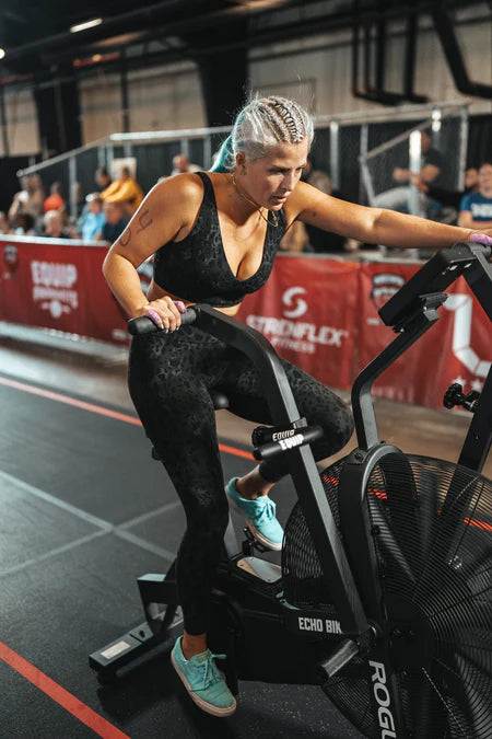 A lady using an Assault Bike in a CrossFit competition.