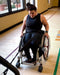 NorCal SCI's Coach Steph Roach pulling a resistance band in her wheelchair.