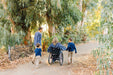 Lindsay Ulrey and her family exploring a path as Lindsay rolls beside them in her wheelchair.