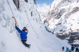 A Paradox Sports climber halfway up an icewall while other groups of climbers are at the base.