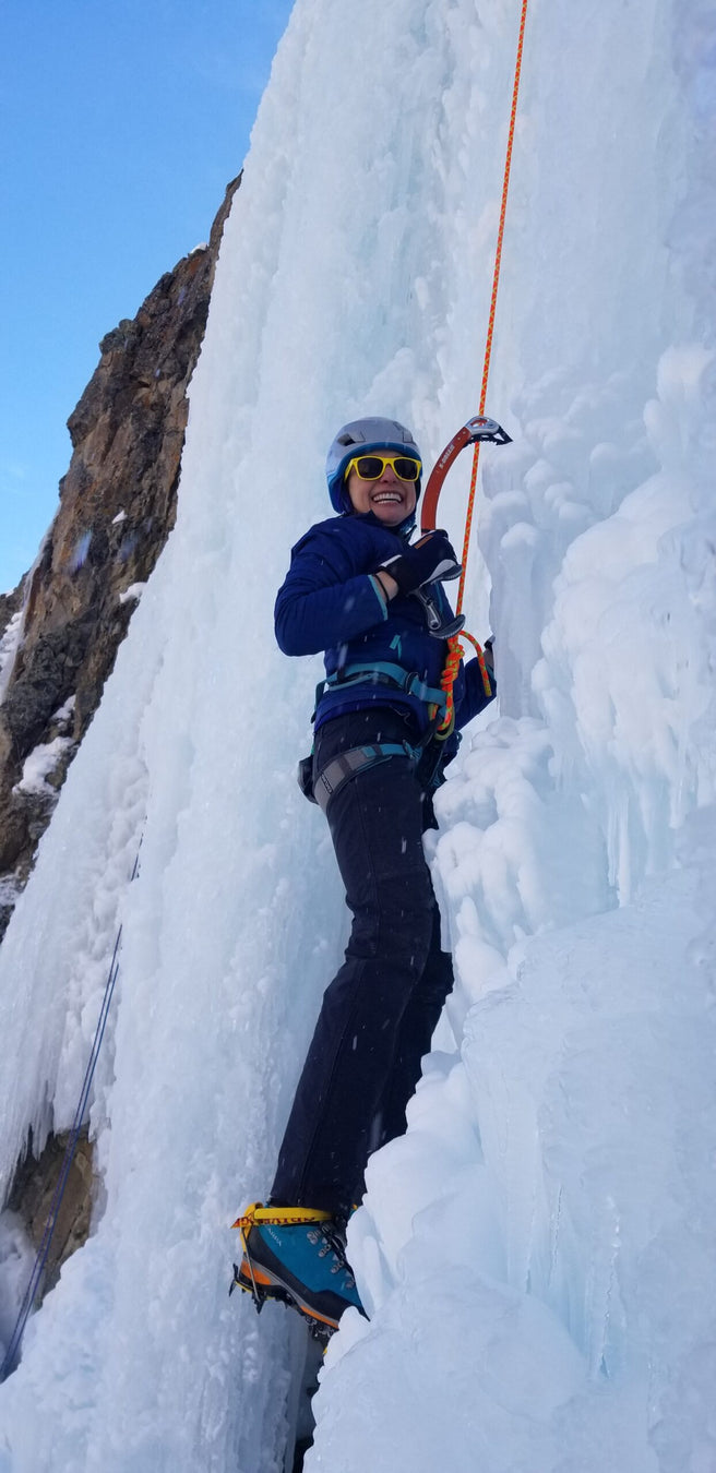 A Paradox Sports climber smiling while ascending the icewall at the Lake City Ice Skills 201.