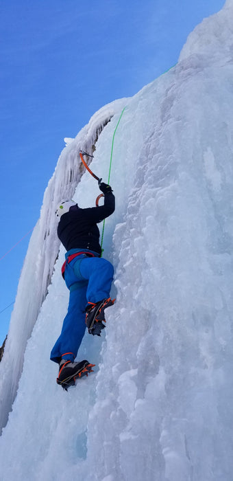 A Paradox Sports climber swinging their ice pick into the icewall at the Lake City Ice Skills 201.