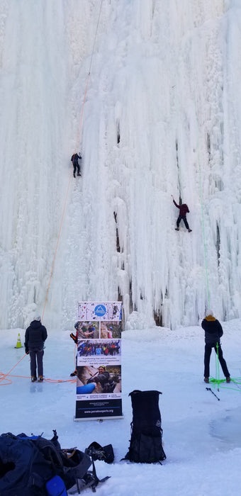 Paradox Sports climbers ascending with a Paradox Sports banner at the base of the Lake City Ice Skills 201.