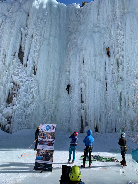 Paradox Sports climbers ascending with a Paradox Sports banner at the base of the Lake City Ice Skills 201.