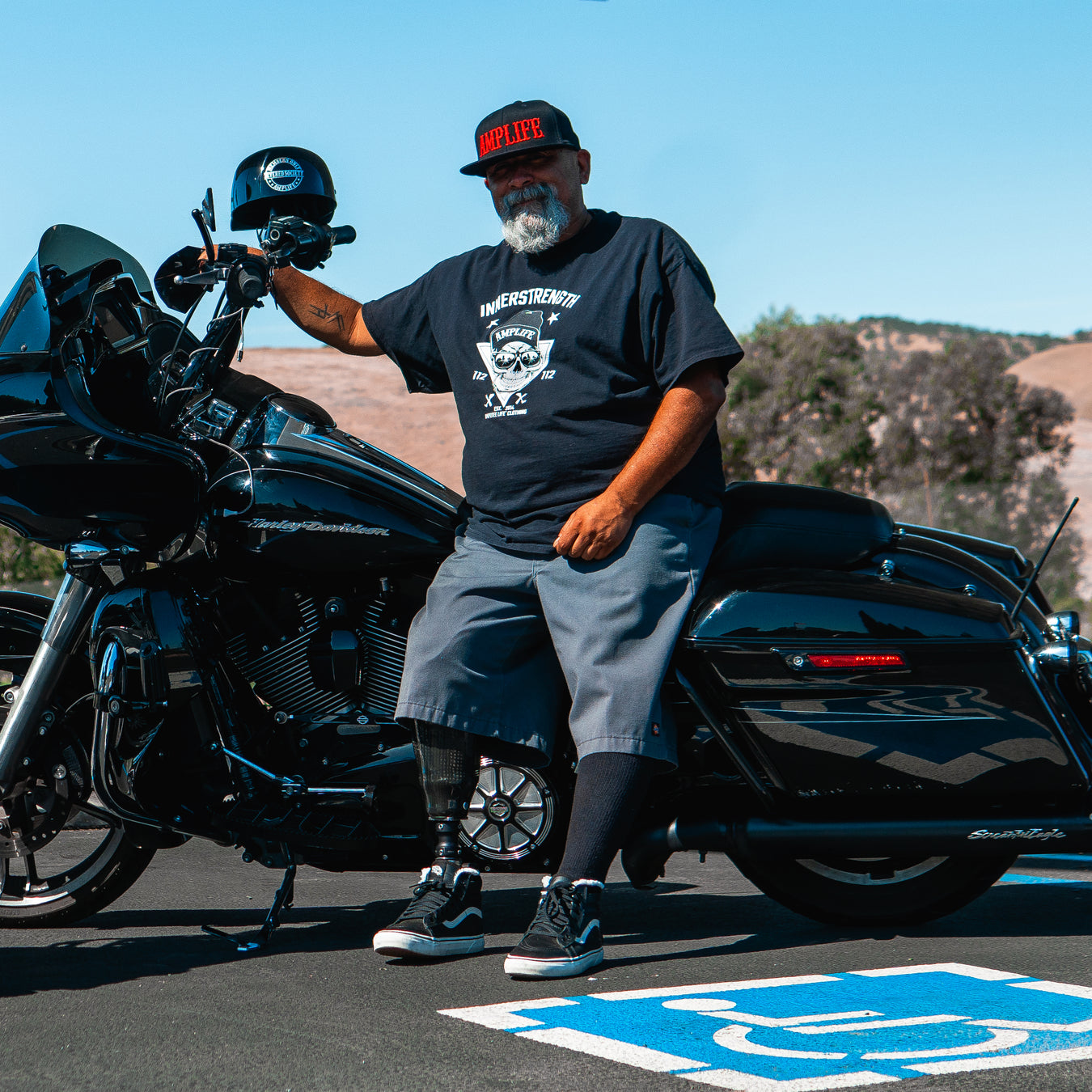 Team Amplife® Ambassador Jason Loftiss wearing the Amplife® Flat Bill Fitted standing next to his motorcycle.