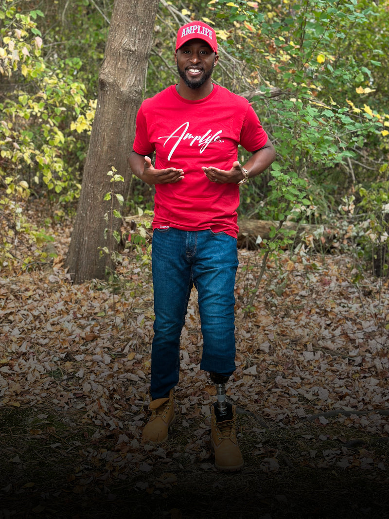 Team Amplife® Ambassador Michael Braxton Jr. wearing the Amplife® Signature T-Shirt  in the woods while emphasizing the design with his hands.