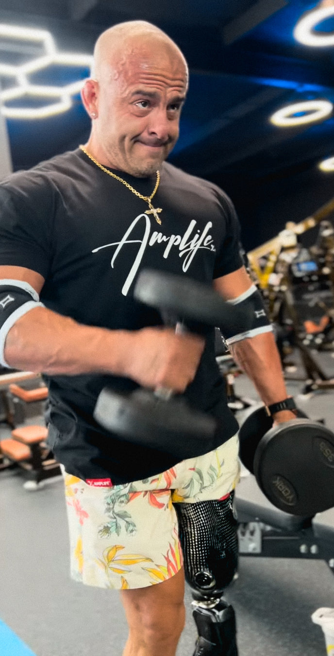 Team Amplife® Ambassador Tomás De La Mora wearing the Amplife® Signature T-Shirt in the gym while performing hammer curls.